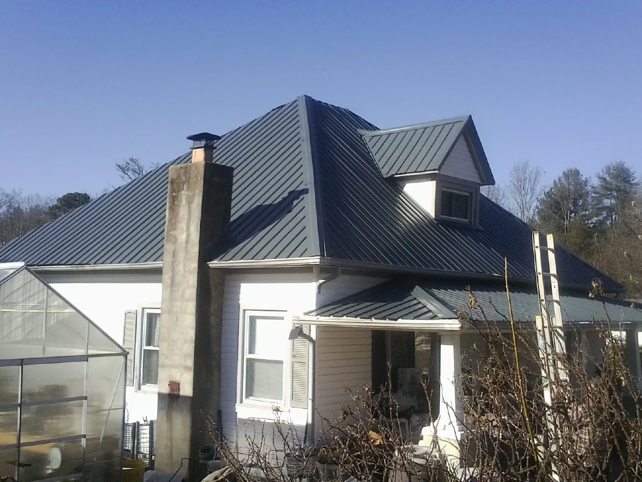 Dark blue standing seam metal roof on a white farmhouse with dormer — Slate & Tile Roof Repair by Roofing Brothers in Thetford Center