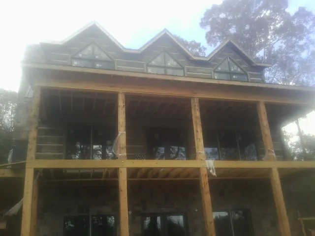 Dormers and porch framing on a large log home under construction — Roof Coating work by our crew in Thetford Center