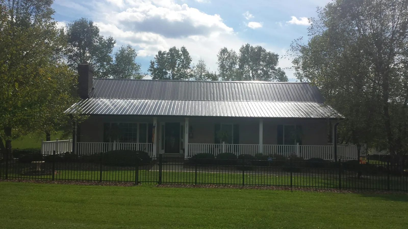 Gray metal roof on a brick ranch with a full width front porch — Gutter Guard Installation work by our crew in Thetford Center