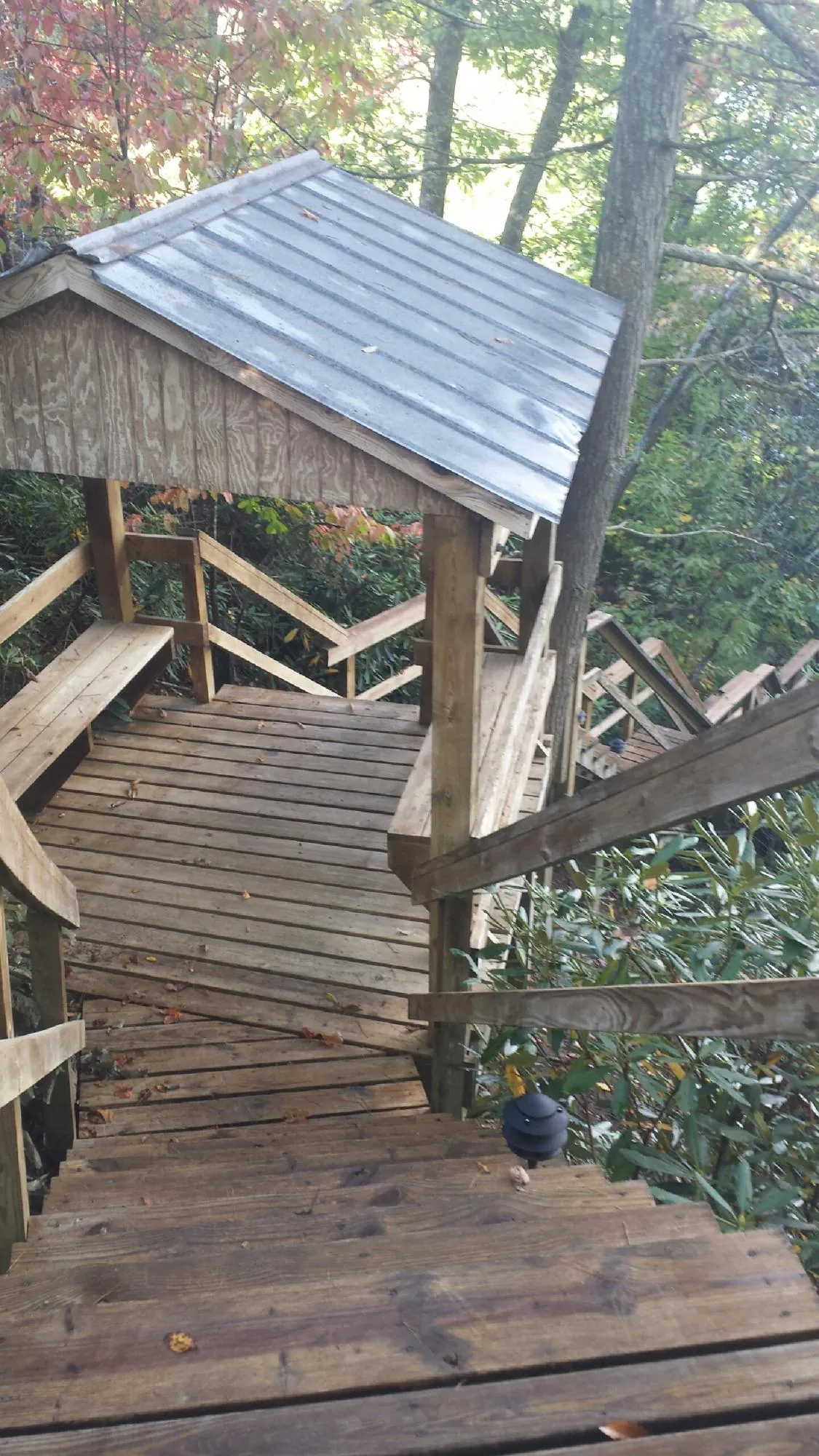 Metal roofed shelter over wooden steps on a wooded walkway — Skylight Repair & Installation work by our crew in Thetford Center