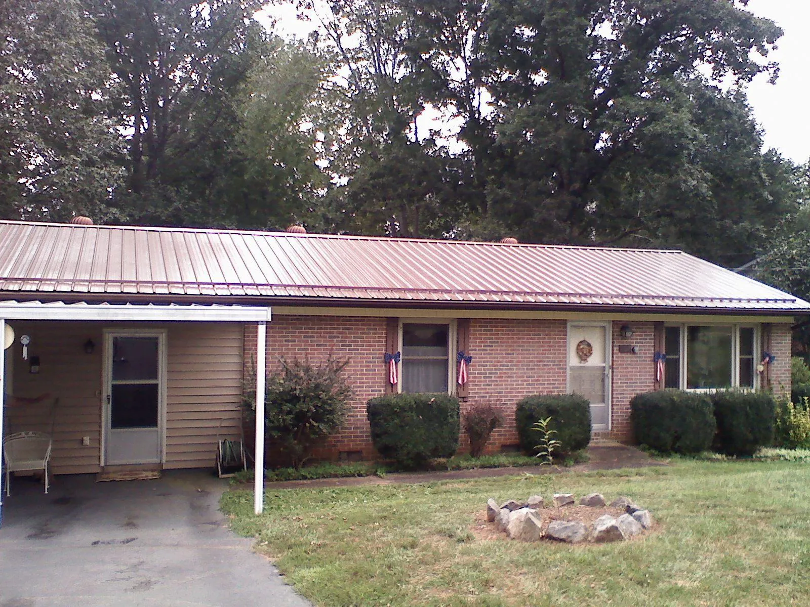 Bronze metal roof and carport on a brick ranch home — Roof Repair work by our crew in Thetford Center