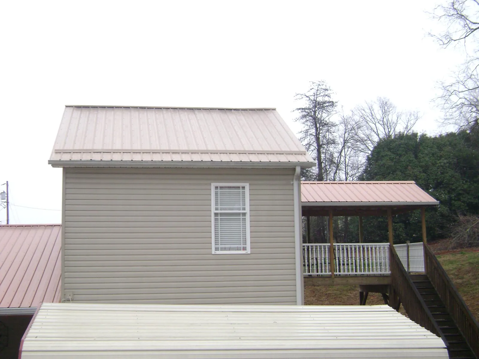 Tan metal roofs on a two story addition and attached porch, from a Roof Replacement job in Thetford Center