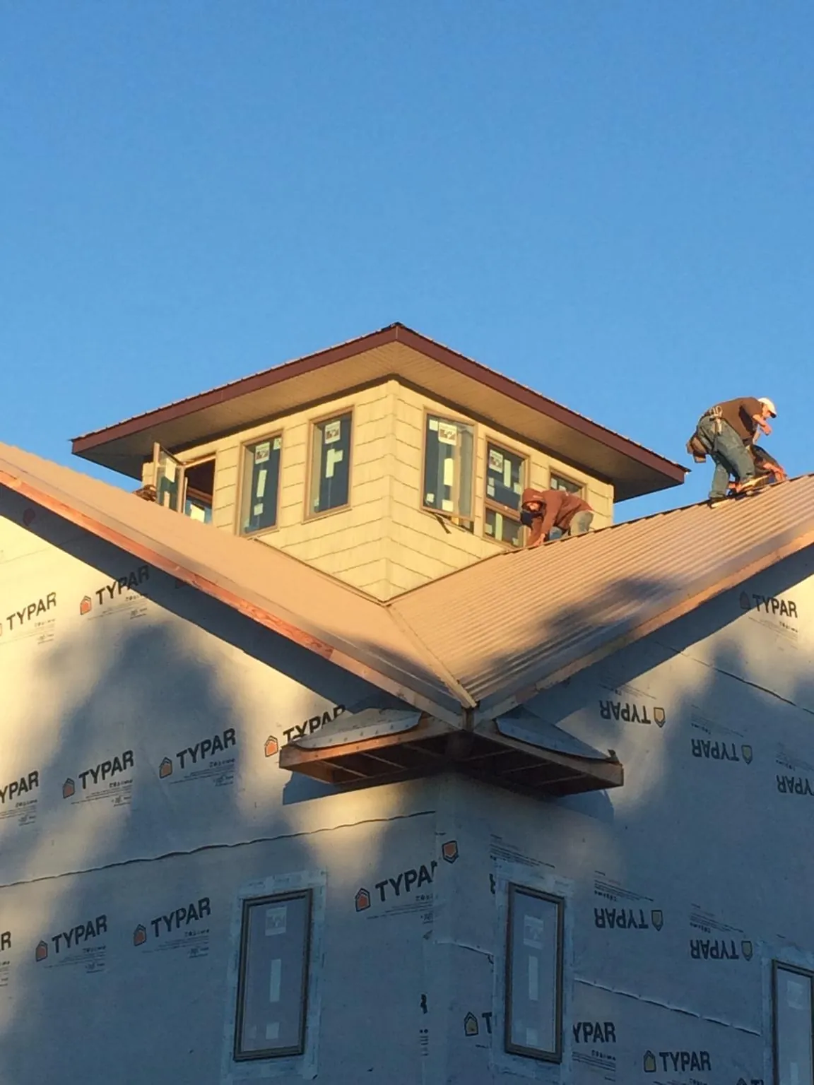 Roofers working around a rooftop cupola on a new metal roof at sunset — Roof Waterproofing in Thetford Center by Roofing Brothers
